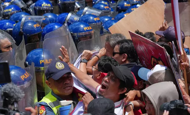 Protesters shout slogans as they are blocked by police while trying to march towards the U.S. Embassy during a May Day rally in Manila, Philippines on Friday, May 1, 2026. (AP Photo/Aaron Favila)