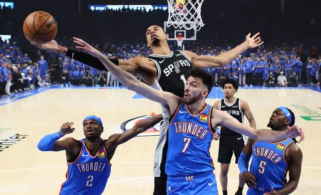 San Antonio Spurs forward Victor Wembanyama (1) and Oklahoma City Thunder center Chet Holmgren (7) reach for a rebound during the first half of Game 1 in a third-round NBA basketball playoffs series Monday, May 18, 2026, in Oklahoma City. (AP Photo/Nate Billings)