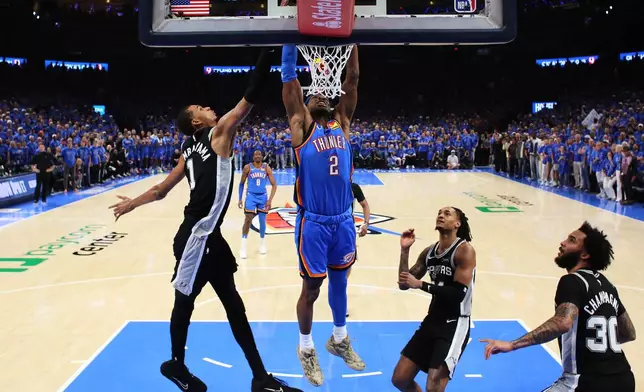 Oklahoma City Thunder guard Shai Gilgeous-Alexander (2) dunks against San Antonio Spurs forward Victor Wembanyama (1) during the first half of Game 1 in a third-round NBA basketball playoffs series Monday, May 18, 2026, in Oklahoma City. (AP Photo/Nate Billings)