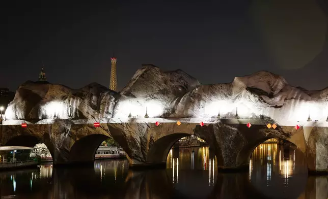 Inflation of the artwork "The Pont Neuf Cave" by French street artist JR on the Pont Neuf bridge, with the Eiffel Tower behind it, Thursday, May 21, 2026, in Paris, before its free opening to the public from June 6 to 28. (AP Photo/Thomas Padilla)