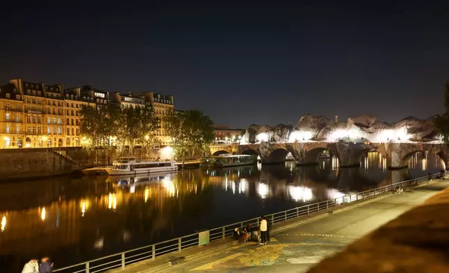 Inflation of the artwork "The Pont Neuf Cave" by French street artist JR on the Pont Neuf bridge, with the Eiffel Tower behind it, Wednesday, May 20, 2026, in Paris, before its free opening to the public from June 6 to 28. (AP Photo/Thomas Padilla)