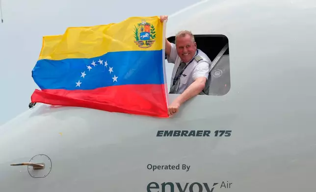 FILE - The pilot of a U.S. aircraft holds a Venezuelan flag from the cockpit window after landing at Simon Bolivar International Airport in Maiquetia, Venezuela, Thursday, April 30, 2026, as direct air service between the United States and Venezuela resumes after seven years. (AP Photo/Ariana Cubillos, File)