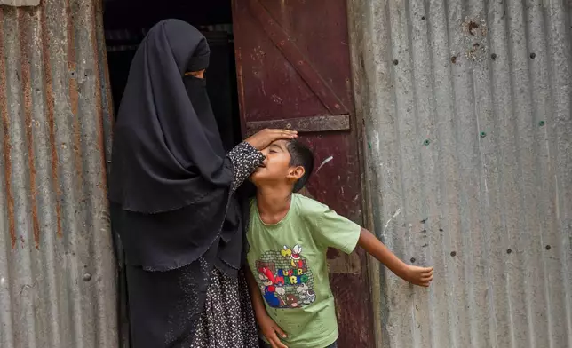 Sadia Islam Sarmin, wife of Mohammad Abdullah Al Mamun touches the forehead of her son at the doorway of their home in Rasulpur village, Mymensingh district, Bangladesh, Friday, April 17, 2026. (AP Photo/Rajib Dhar)