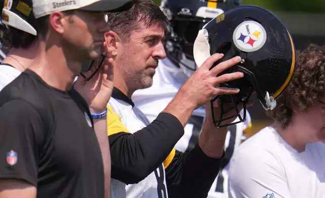 Pittsburgh Steelers quarterback Aaron Rodgers, center, puts on his helmet whole participating in the football team's OTA workout in Pittsburgh, Monday, May 18, 2026. (AP Photo/Gene J. Puskar)