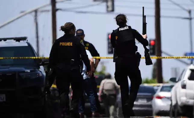 People carry weapons at the scene of a shooting outside the Islamic Center of San Diego Monday, May 18, 2026, in San Diego. (AP Photo/Gregory Bull)