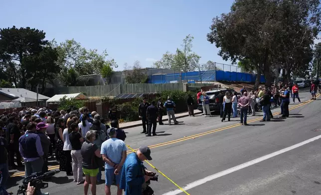 A crowd gathers near the scene of a shooting outside the Islamic Center of San Diego Monday, May 18, 2026, in San Diego. (AP Photo/Gregory Bull)