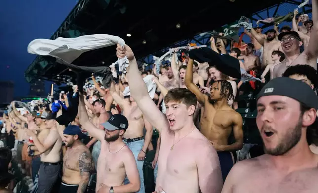 Fans cheer with their shirts off after heading to the upper deck outfield seating during the ninth inning of a baseball game between the Detroit Tigers and Cleveland Guardians Tuesday, May 19, 2026, in Detroit. (AP Photo/Paul Sancya)