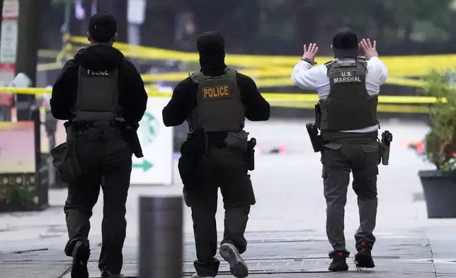 U.S. Marshals and other police walk toward a crime scene after responding to reports of shots fired near the White House, Saturday, May 23, 2026, in Washington. (AP Photo/Alex Brandon)