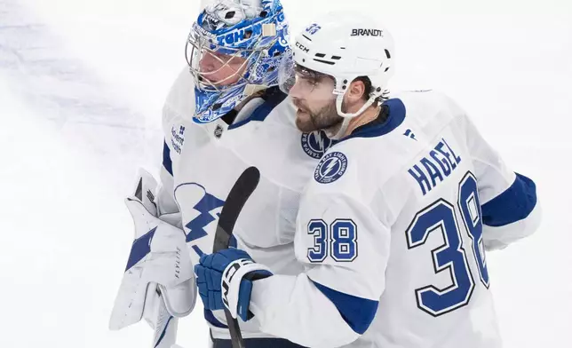 Tampa Bay Lightning's Brandon Hagel (38) congratulates goaltender Andrei Vasilevskiy, left, after their team defeated the Montreal Canadiens in overtime of Game 6 in the first round of an NHL hockey Stanley Cup playoff series in Montreal, Friday, May 1, 2026. (Christinne Muschi/The Canadian Press via AP)