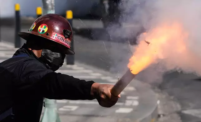 A miner launches a firecracker at police during an anti-government protest in La Paz, Bolivia, Monday, May 18, 2026. (AP Photo/Juan Karita)
