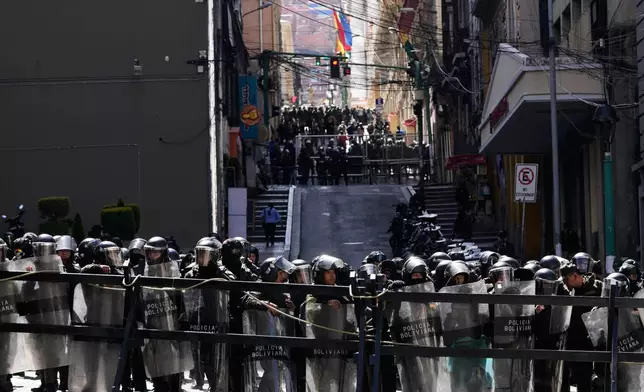 Police stand guard behind a fence during anti-government protests near the government palace in La Paz, Bolivia, Monday, May 18, 2026. (AP Photo/Juan Karita)