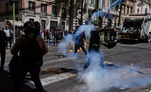 A protester returns a tear gas canister to police during an anti-government protest in La Paz, Bolivia, Monday, May 18, 2026. (AP Photo/Juan Karita)