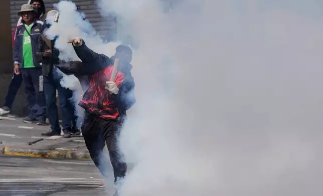 A protester returns a tear gas canister to police during an anti-government protest in La Paz, Bolivia, Monday, May 18, 2026. (AP Photo/Juan Karita)