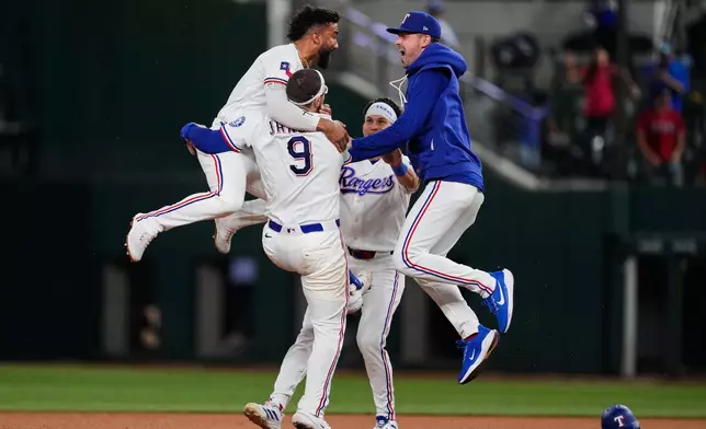 Texas Rangers' Ezequiel Duran, left, Danny Jansen (9) Sam Haggerty, rear, and MacKenzie Gore, right, celebrate Jansen's run-scoring single in the ninth inning of a baseball game against the Arizona Diamondbacks Wednesday, May 13, 2026, in Arlington, Texas. (AP Photo/Tony Gutierrez)