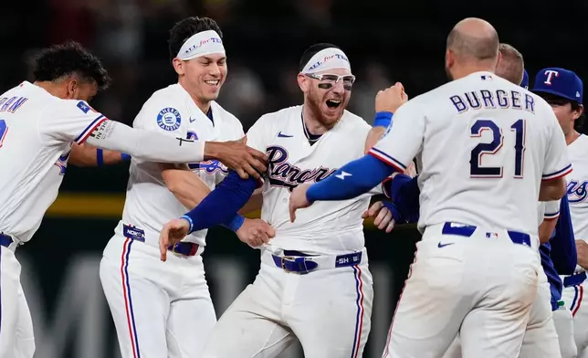 Texas Rangers' Ezequiel Duran, from left, Sam Haggerty, Danny Jansen and Jake Burger (21), celebrate Jansen's run-scoring single in the ninth inning of a baseball game against the Arizona Diamondbacks Wednesday, May 13, 2026, in Arlington, Texas. (AP Photo/Tony Gutierrez)