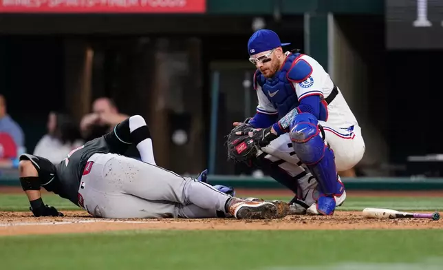 Texas Rangers catcher Danny Jansen kneels by Arizona Diamondbacks' Lourdes Gurriel Jr. who fouled a pitch onto legs in the fourth inning of a baseball game Wednesday, May 13, 2026, in Arlington, Texas. (AP Photo/Tony Gutierrez)