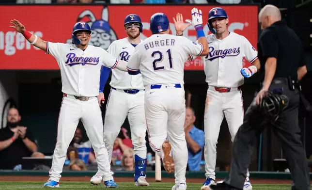 Texas Rangers' Alejandro Osuna, from left, Danny Jansen, Jake Burger (21) and Evan Carter, second from right, celebrate Burger's three-run home run as umpire Jansen Visconti, right, stands by the plate in the fifth inning of a baseball game against the Arizona Diamondbacks Wednesday, May 13, 2026, in Arlington, Texas. (AP Photo/Tony Gutierrez)