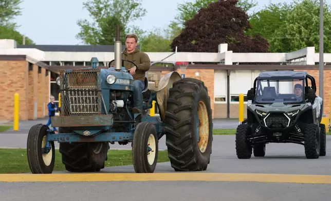 Gavin McFadden arrives on his Ford 5000 tractor during Tractor Day for graduating seniors at Airport High School Friday, May 22, 2026, in Carleton, Mich. (AP Photo/Paul Sancya)