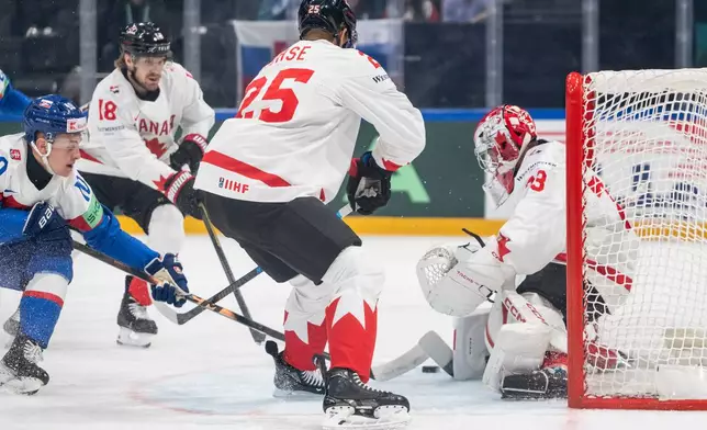 Slovakia's Adam Sykora, left, challenges Canada's goaltender Jet Greaves, Darnell Nurse and Robert Thomas, from right, during the 2026 IIHF Men's Ice Hockey World Championship preliminary round group B game between Slovakia and Canada,, in Fribourg, Switzerland, Sunday, May 24, 2026. (Alessandro della Valle/Keystone via AP)