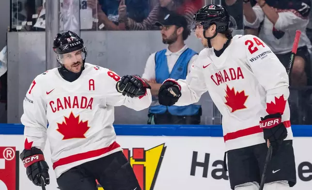 Canada's Dylan Cozens, right, celebrates with teammate Sidney Crosby after scoring during the 2026 IIHF Men's Ice Hockey World Championship preliminary round group B game between Slovakia and Canada, in Fribourg, Switzerland, Sunday, May 24, 2026. (Alessandro della Valle/Keystone via AP)