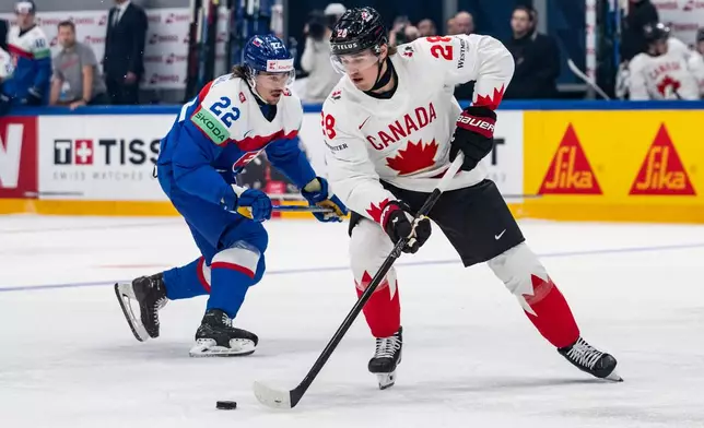 Canada's Zach Whitecloud, right, vies for the puck against Slovakia's Kristian Pospisil during the 2026 IIHF Men's Ice Hockey World Championship preliminary round group B game between Slovakia and Canada, in Fribourg, Switzerland, Sunday, May 24, 2026. (Alessandro della Valle/Keystone via AP)