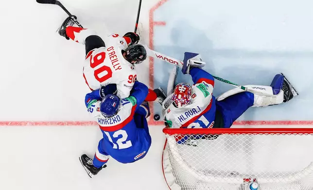 Canada's Ryan O'Reilly, left, challenges Slovakia's Samuel Knazko, bottom left, and Slovakia's goaltender Samuel Hlavaj, right, during the 2026 IIHF Men's Ice Hockey World Championship preliminary round group B game between Slovakia and Canada, in Fribourg, Switzerland, Sunday, May 24, 2026. (Alessandro della Valle/Keystone via AP)