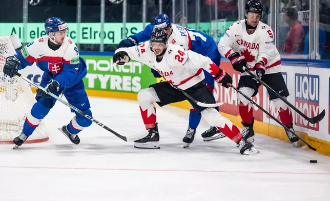 Slovakia's Oliver Okuliar, Canada's Dylan Cozens, Slovakia's Martin Pospisil and Canada's Denton Mateychuk, from left, fight for the puck during the 2026 IIHF Men's Ice Hockey World Championship preliminary round group B game between Slovakia and Canada, in Fribourg, Switzerland, Sunday, May 24, 2026. (Alessandro della Valle/Keystone via AP)