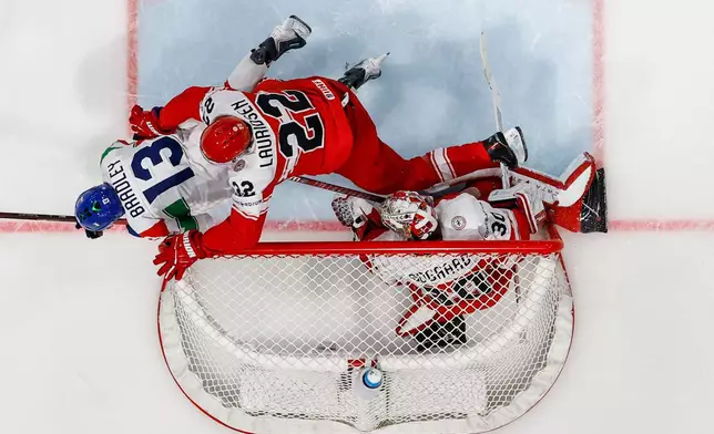 Denmark's Markus Lauridsen, center, falls on Italy's Matt Bradley, left, next to Denmark's goaltender Mads Sogaard, right, during the 2026 IIHF Men's Ice Hockey World Championship preliminary round group B game between Denmark and Italy in Fribourg, Switzerland, Sunday, May 24, 2026. (Alessandro della Valle/Keystone via AP)