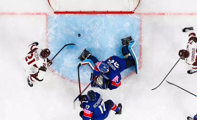 Latvia's Rudolfs Balcers, left, scores his side's third goal during the 2026 IIHF Men's Ice Hockey World Championship preliminary round group A match between Great Britain and Latvia in Zurich, Switzerland, Sunday, May 24, 2026. (Andreas Becker/Keystone via AP)