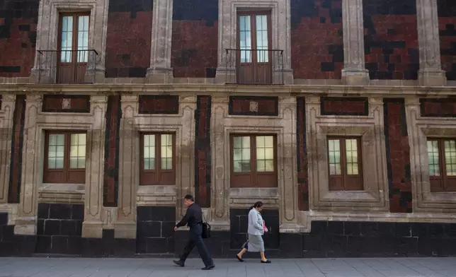 FILE - Pedestrians walk past a slightly tilted historic building in downtown Mexico City, June 15, 2016. The city was built on a drained lake bed and many buildings are noticeably tilted, from sinking unevenly into the soft earth over decades or centuries. (AP Photo/Rebecca Blackwell, File)
