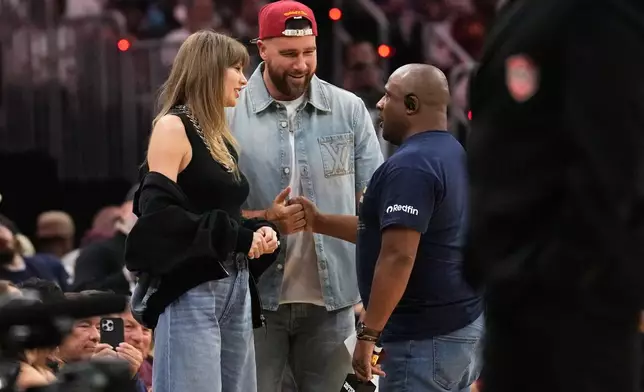 Taylor Swift and Travis Kelce talk with Ahmaad Crump, Cleveland Cavaliers' arena host, during a timeout in the first half of Game 3 in the Eastern Conference finals NBA basketball playoffs series against the New York Knicks in Cleveland, Monday, May 24, 2027. (AP Photo/Sue Ogrocki)