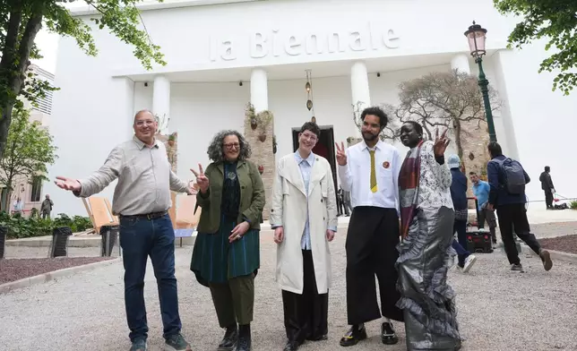 From left, Venice Biennale Art curators, Siddhartha Mitter, Rasha Salti Gabe Beckhurst Feijoo, Rory Tsapayi, and Marie Helene Pereira pose in front of the main entrance at the Venice 2026 Biennale Art, in Venice, Italy, Tuesday, May 5, 2026. (AP Photo/Luca Bruno)
