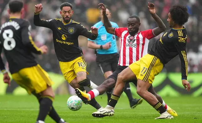 Sunderland's Lutsharel Geertruida is challenged by Manchester United's Matheus Cunha and Joshua Zirkzee, right, during the English Premier League soccer match between Sunderland and Manchester United in Sunderland, England, Saturday May 9, 2026. (Owen Humphreys/PA via AP)