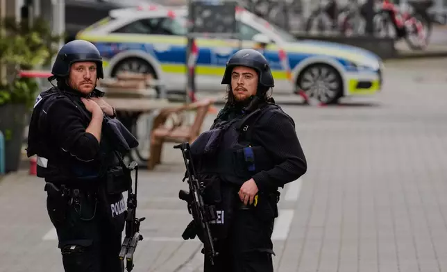 Police officers stand at the scene of a hostage-taking at a bank branch in Sinzig, Germany, Friday, May 8, 2026. (AP Photo/Michael Probst)