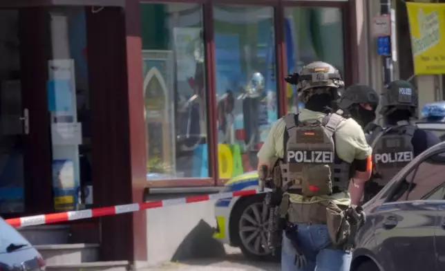 Police officers stand at the scene of an incident where, according to reports, a hostage situation has occurred at a bank branch in Sinzig, Germany, Friday, May 8, 2026. (Thomas Frey/dpa via AP)