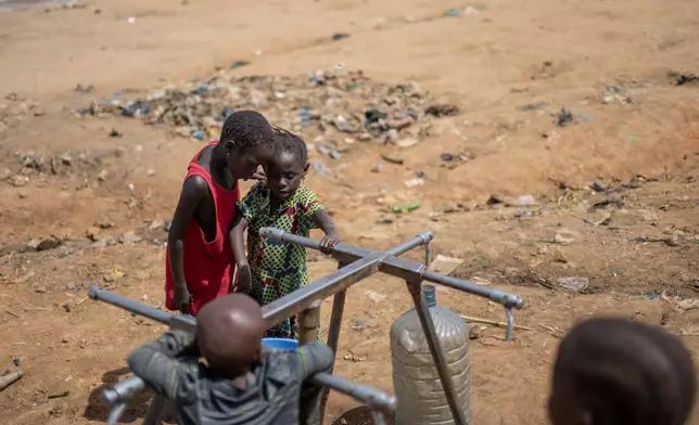 Internally displaced children play with a broken water pump at the camp on the property of the city's ISP (Institut Supérieur Pédagogique) in Bunia, Congo, Tuesday, May 26, 2026. (AP Photo/Moses Sawasawa)
