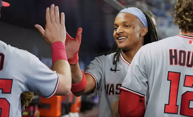 Washington Nationals' CJ Abrams is congratulated in the dugout after scoring on a sacrifice fly hit by Daylen Lile during the third inning of a baseball game against the Miami Marlins, Saturday, May 9, 2026, in Miami. (AP Photo/Lynne Sladky)