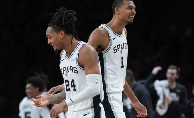 San Antonio Spurs guard Devin Vassell (24) and forward Victor Wembanyama (1) celebrate a score against the Minnesota Timberwolves during the first half of Game 6 of an NBA basketball second-round playoffs series in Minneapolis, Friday, May 15, 2026. (AP Photo/Abbie Parr)