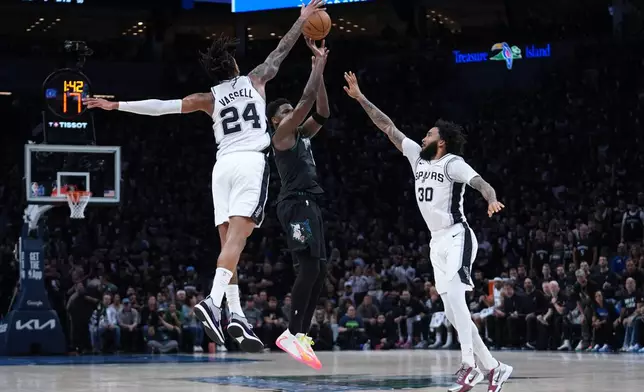 Minnesota Timberwolves guard Anthony Edwards, center, shoots against San Antonio Spurs guard Devin Vassell (24) and forward Julian Champagnie (30) during the first half of Game 6 of an NBA basketball second-round playoffs series against the San Antonio Spurs in Minneapolis, Friday, May 15, 2026. (AP Photo/Abbie Parr)