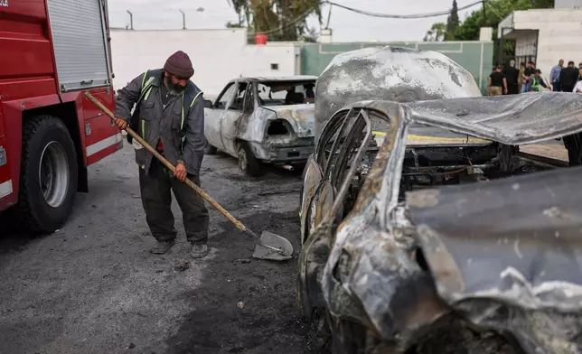 A worker cleans near damaged cars at the site of an explosion outside a Defense Ministry building in Damascus, Syria, Tuesday, May 19, 2026. (AP Photo/Ghaith Alsayed)