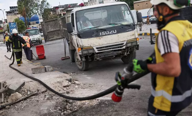 Workers clean the area at the site of an explosion outside a Defense Ministry building in Damascus, Syria, Tuesday, May 19, 2026. (AP Photo/Ghaith Alsayed)
