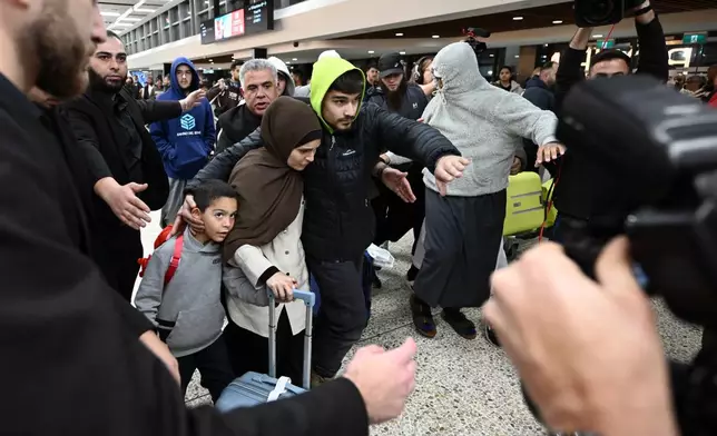 A group of supporters surround a woman with alleged ties to the Islamic State as she arrives with a child at Melbourne international Airport, in Melbourne, Australia, Thursday, May 7, 2026. (Joel Carrett/AAP Image via AP)