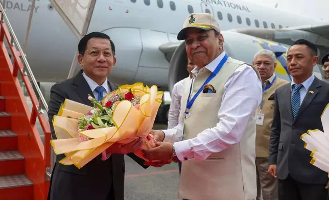 In this photo provided by Myanmar Military True News Information Team on Saturday, May 30, 2026, Myanmar President Min Aung Hlaing, left, receives flowers from Bihar State Governor and retired Lt- General Syed Ata Hasnian, right, upon arrival at Gaya airport, India on May 30. (Myanmar Military True News Information Team via AP Photo)