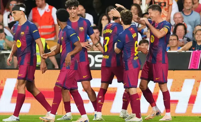 Barcelona's Robert Lewandowski, right, is congratulated after scoring his side's opening goal during the Spanish La Liga soccer match between Valencia and FC Barcelona in Valencia, Spain, Saturday, May 23, 2026. (AP Photo/Alberto Saiz)