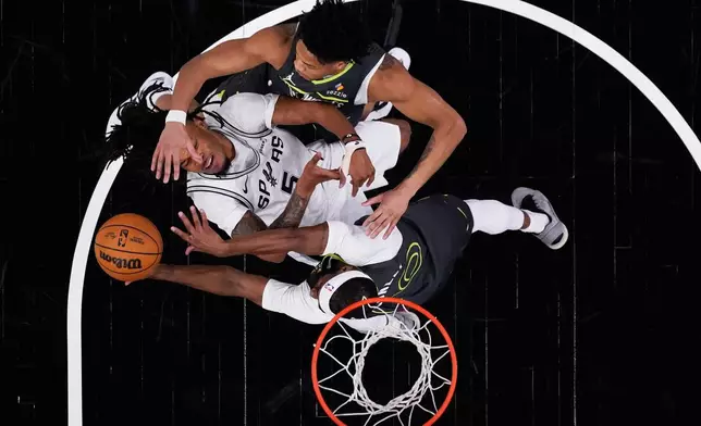 San Antonio Spurs guard Stephon Castle (5) is blocked by fouled by Minnesota Timberwolves guard Mike Conley (10) and guard Terrence Shannon Jr. (1) during the first half in Game 2 of a second-round NBA playoffs basketball series in San Antonio, Wednesday, May 6, 2026. (AP Photo/Eric Gay)