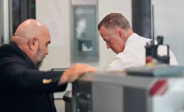 Neuralink CEO Jared Birchall, right, walks through security at the U.S. District Court in Oakland, Calif., Thursday, April 30, 2026. (AP Photo/Godofredo A. Vásquez)