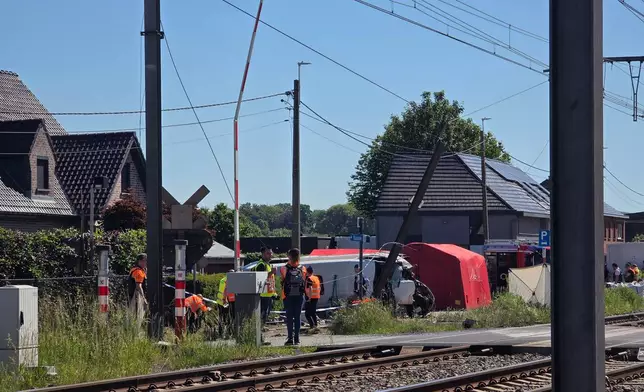 Rescue workers on the scene of a crash between a train and vehicle in Buggenhout, Belgium, Tuesday, May 26, 2026. (AP Photo/Koen Baten)