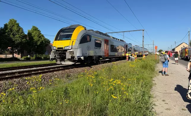 Rescue workers on the scene of a crash between a train and vehicle in Buggenhout, Belgium, Tuesday, May 26, 2026. (AP Photo/Koen Baten)