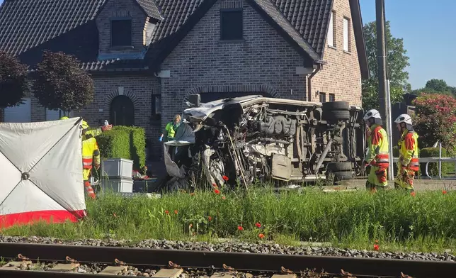 Rescue workers on the scene of a crash between a train and vehicle in Buggenhout, Belgium, Tuesday, May 26, 2026. (AP Photo/Koen Baten)