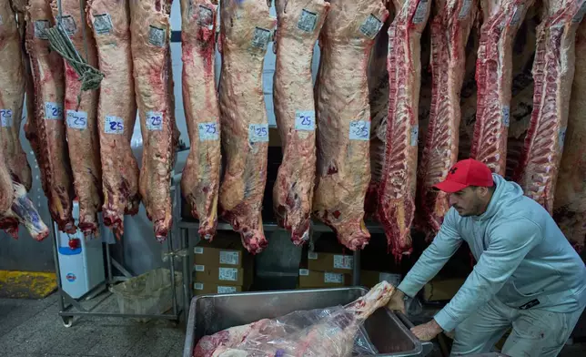 A worker stacks beef inside a fridge at a butcher shop in the Mataderos meat market in Buenos Aires, Argentina, Thursday, May 14, 2026. (AP Photo/Rodrigo Abd)